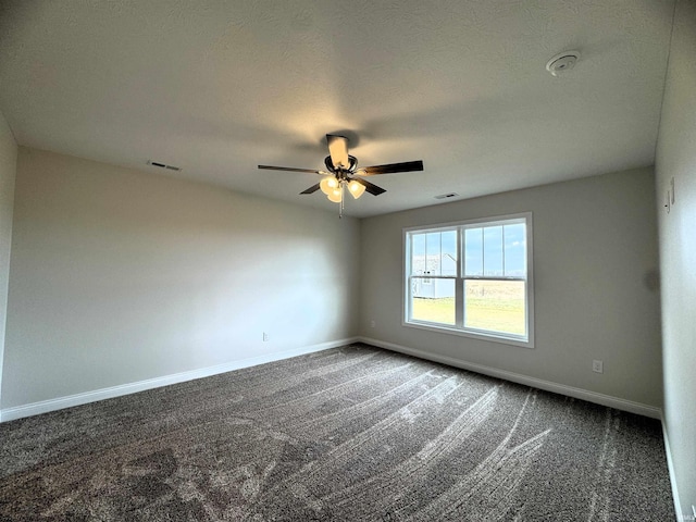 spare room with visible vents, baseboards, ceiling fan, a textured ceiling, and dark colored carpet