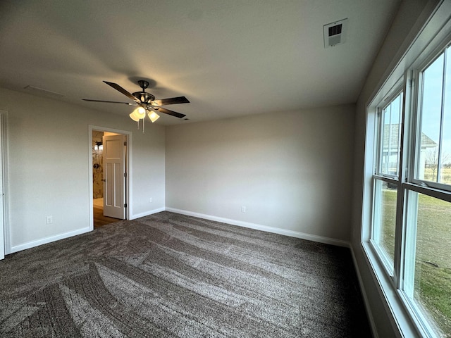 unfurnished room featuring visible vents, dark carpet, a ceiling fan, and baseboards