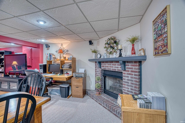 office space featuring a drop ceiling, carpet floors, and a brick fireplace