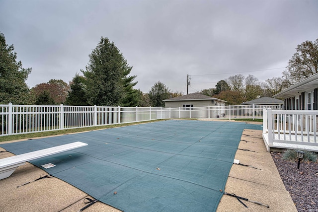 view of swimming pool with a patio area and a diving board