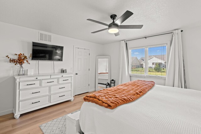 bedroom with light hardwood / wood-style floors, ceiling fan, and a textured ceiling