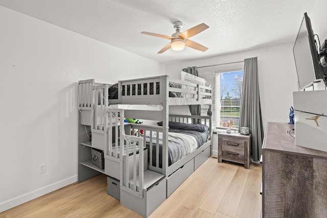 bedroom with light hardwood / wood-style floors, ceiling fan, and a textured ceiling