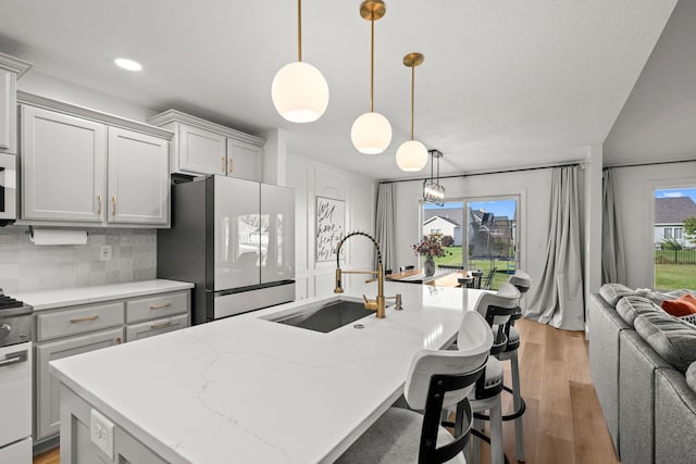 kitchen with an island with sink, white appliances, a healthy amount of sunlight, and backsplash