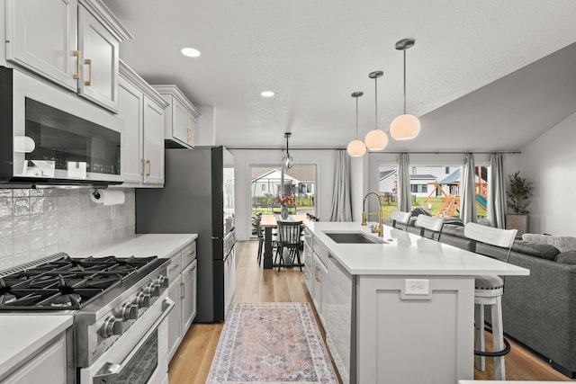 kitchen featuring stainless steel appliances, sink, a kitchen breakfast bar, an island with sink, and light wood-type flooring