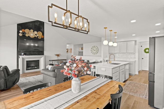 dining space featuring light wood-type flooring, sink, and a notable chandelier