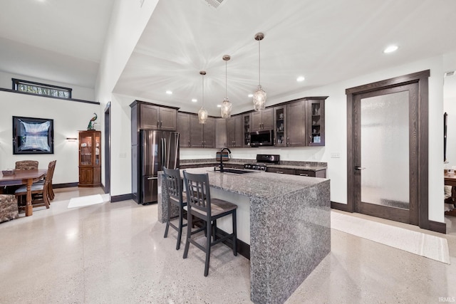 kitchen featuring a center island with sink, dark brown cabinetry, hanging light fixtures, sink, and appliances with stainless steel finishes