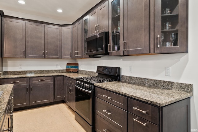 kitchen featuring dark brown cabinetry, light stone counters, and black gas stove