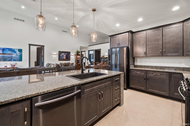 kitchen with dark brown cabinetry, sink, light stone countertops, appliances with stainless steel finishes, and decorative light fixtures