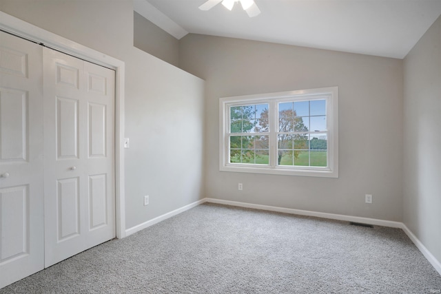 unfurnished bedroom with a closet, vaulted ceiling, carpet flooring, and ceiling fan