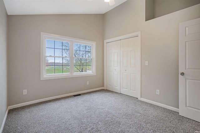 unfurnished bedroom featuring carpet flooring, lofted ceiling, and a closet