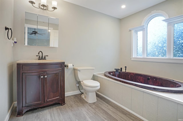 bathroom with wood-type flooring, vanity, toilet, a washtub, and ceiling fan