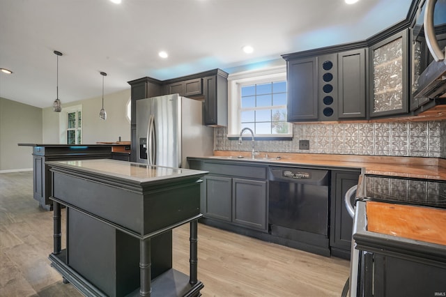 kitchen featuring stainless steel appliances, a kitchen island, light wood-type flooring, hanging light fixtures, and sink