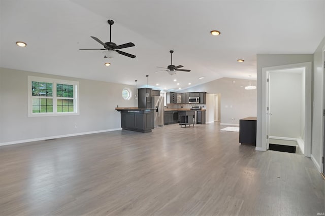 unfurnished living room with lofted ceiling, wood-type flooring, and ceiling fan with notable chandelier