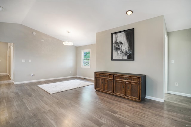 unfurnished room featuring lofted ceiling and hardwood / wood-style floors