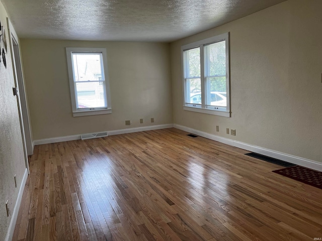 unfurnished room featuring hardwood / wood-style flooring and a textured ceiling