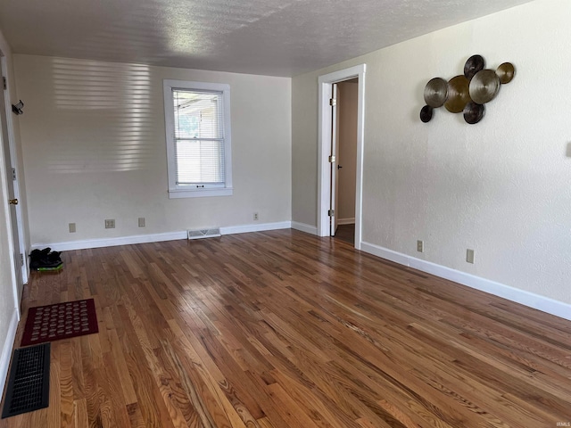 spare room with a textured ceiling and dark hardwood / wood-style floors