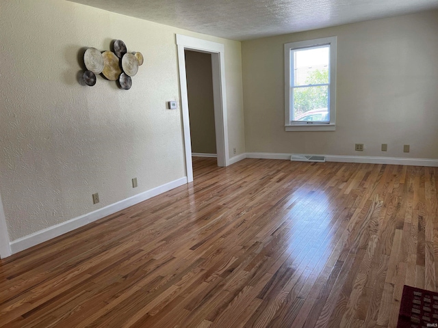 spare room featuring a textured ceiling and hardwood / wood-style flooring