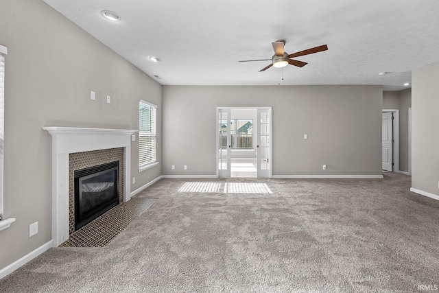 unfurnished living room with light carpet, a textured ceiling, a tile fireplace, and ceiling fan