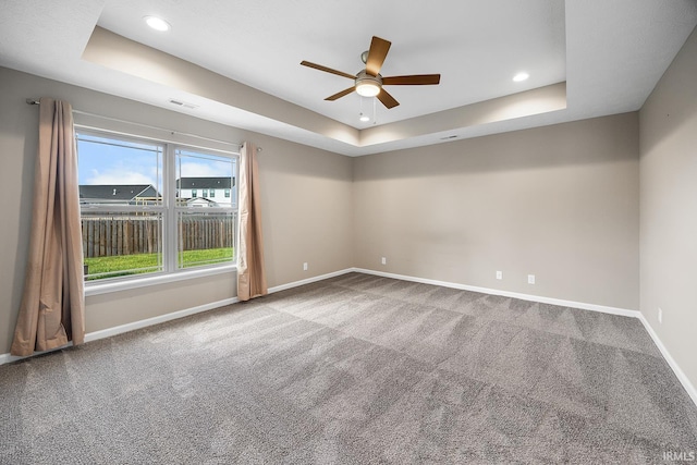 unfurnished room with ceiling fan, a raised ceiling, and carpet floors