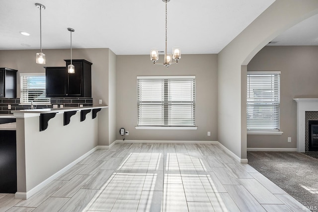 kitchen with a breakfast bar area, plenty of natural light, decorative light fixtures, and tasteful backsplash