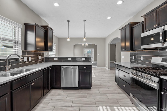 kitchen featuring a textured ceiling, stainless steel appliances, sink, and decorative light fixtures