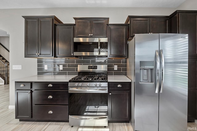 kitchen featuring dark brown cabinets, light wood-type flooring, appliances with stainless steel finishes, and tasteful backsplash