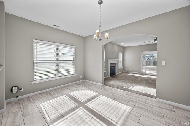 unfurnished living room with ceiling fan with notable chandelier