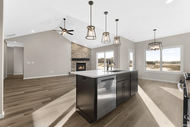 kitchen featuring dark wood-type flooring, sink, decorative light fixtures, appliances with stainless steel finishes, and an island with sink