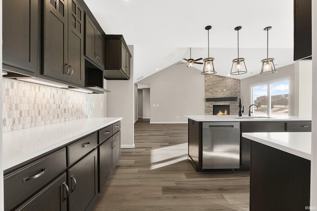 kitchen featuring lofted ceiling, dishwasher, a fireplace, decorative backsplash, and decorative light fixtures