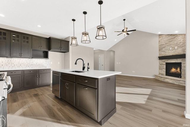 kitchen with appliances with stainless steel finishes, sink, decorative backsplash, a kitchen island with sink, and dark brown cabinets