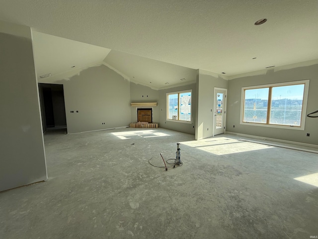 unfurnished living room featuring vaulted ceiling and a textured ceiling