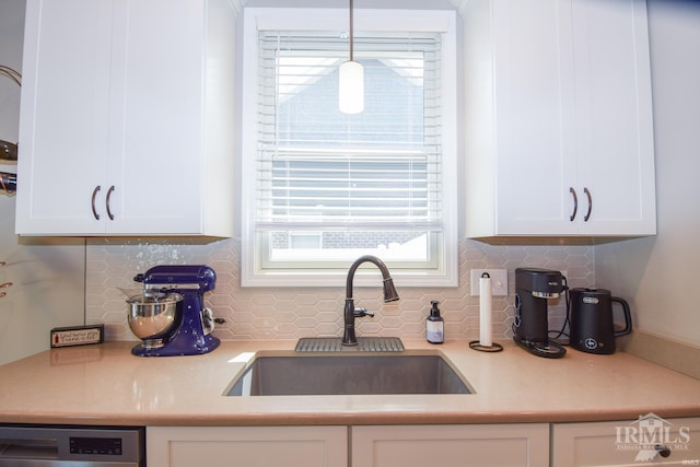 kitchen featuring white cabinetry, decorative backsplash, hanging light fixtures, and sink