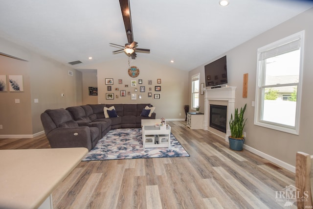 living room featuring light hardwood / wood-style flooring, ceiling fan, and vaulted ceiling