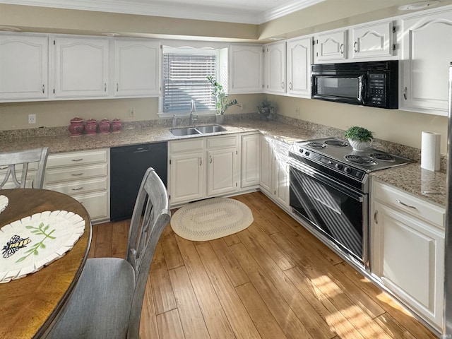 kitchen featuring light wood-type flooring, white cabinetry, sink, and black appliances