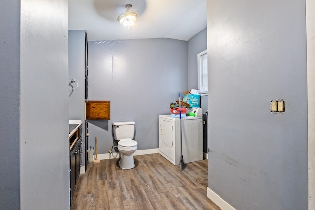 bathroom featuring hardwood / wood-style flooring, ceiling fan, washer / dryer, and toilet