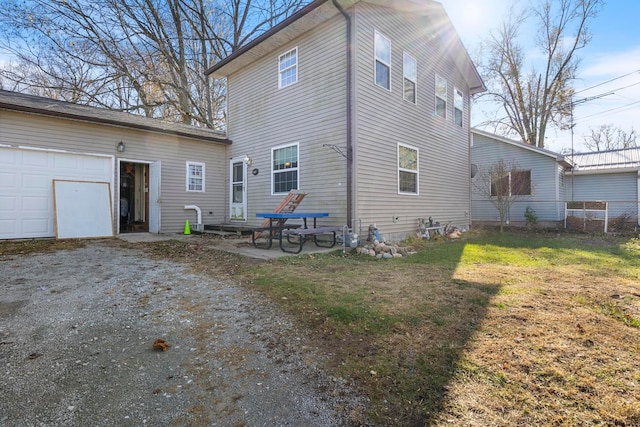 rear view of house with a lawn, a garage, and a patio area