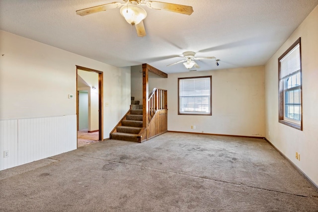 empty room featuring a textured ceiling, light colored carpet, and ceiling fan