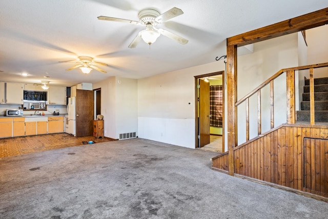 unfurnished living room with wooden walls, sink, and light carpet