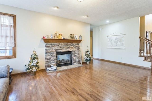 living room with a textured ceiling, a fireplace, and hardwood / wood-style flooring