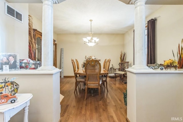 dining room featuring hardwood / wood-style flooring, ornate columns, and a notable chandelier