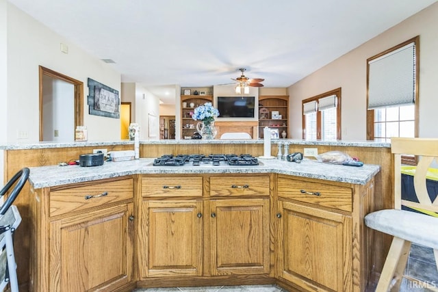 kitchen featuring light stone counters, ceiling fan, and stainless steel gas stovetop