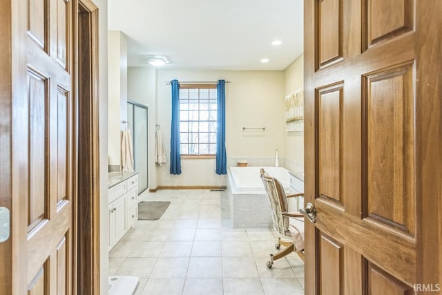 bathroom featuring a relaxing tiled tub, tile patterned flooring, and vanity