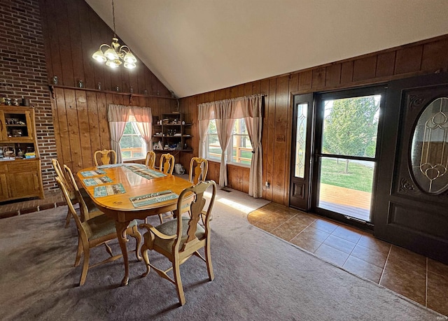 dining space with plenty of natural light, wooden walls, and an inviting chandelier