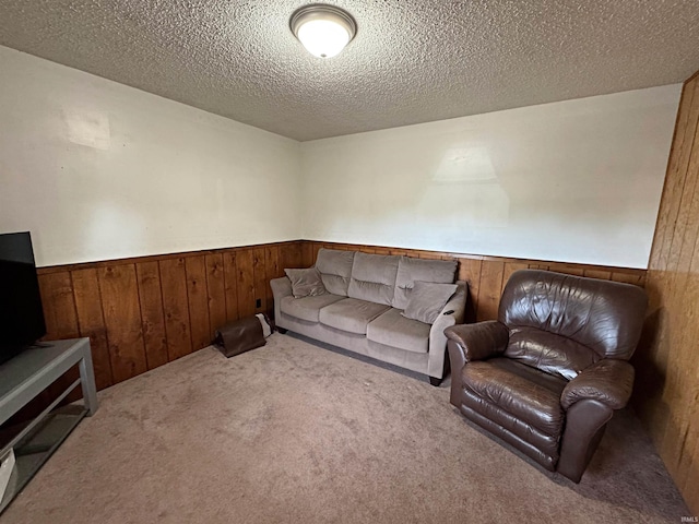 living room with wood walls, a textured ceiling, and carpet floors