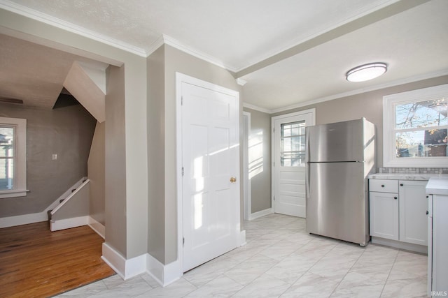 kitchen featuring ornamental molding, a healthy amount of sunlight, and stainless steel fridge