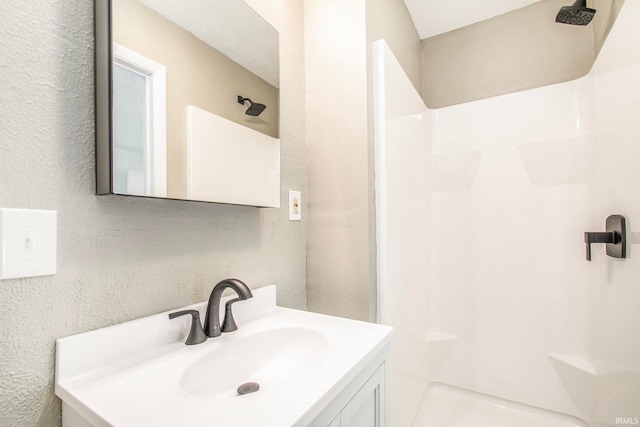 bathroom featuring walk in shower and vanity