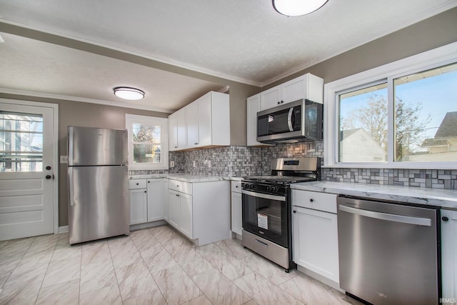 kitchen with ornamental molding, white cabinetry, a healthy amount of sunlight, and stainless steel appliances