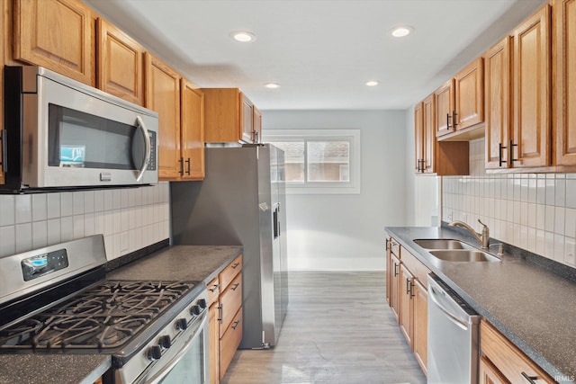 kitchen featuring decorative backsplash, stainless steel appliances, sink, and light hardwood / wood-style flooring