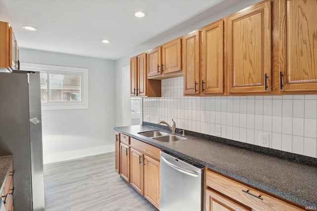 kitchen with stainless steel appliances, sink, light wood-type flooring, and decorative backsplash