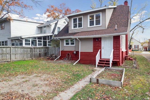 rear view of house with a sunroom and a yard